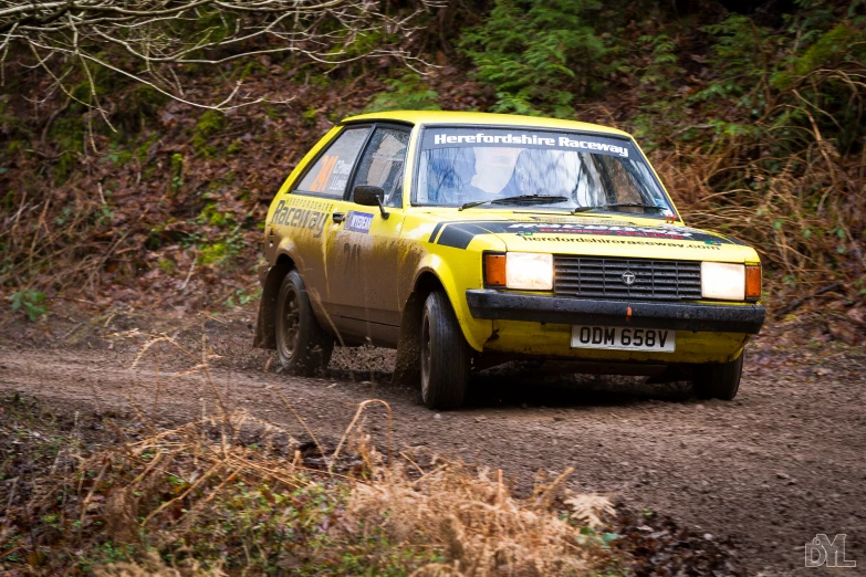 a yellow car with the number six on it is coming up a dirt road