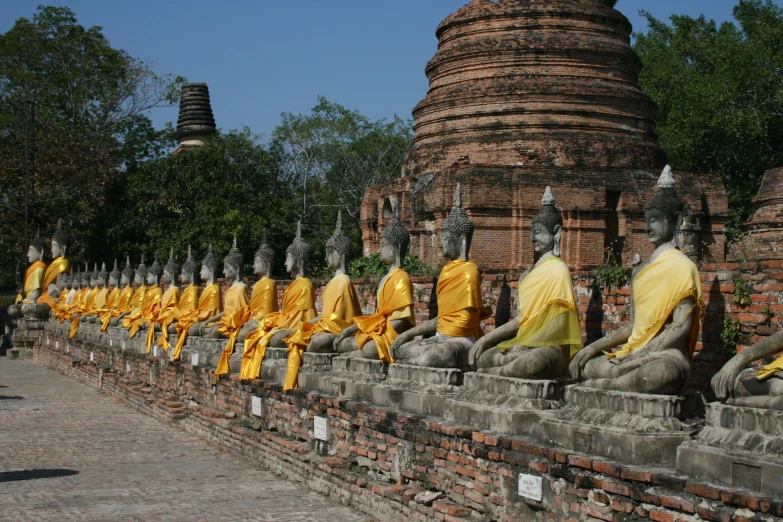 a row of buddha statues that are sitting near a large round object