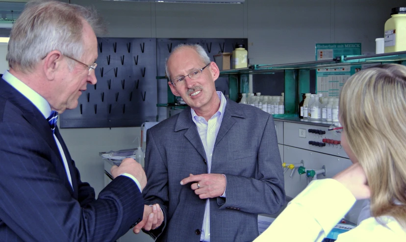 two men wearing suits talking to a woman