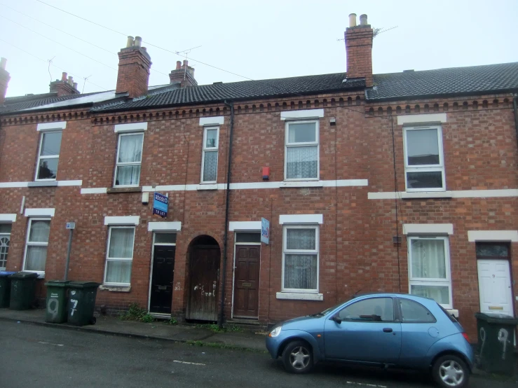 a small car parked in front of a brick building