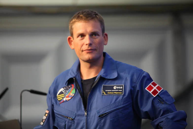 a man in a blue nasa suit holding a podium