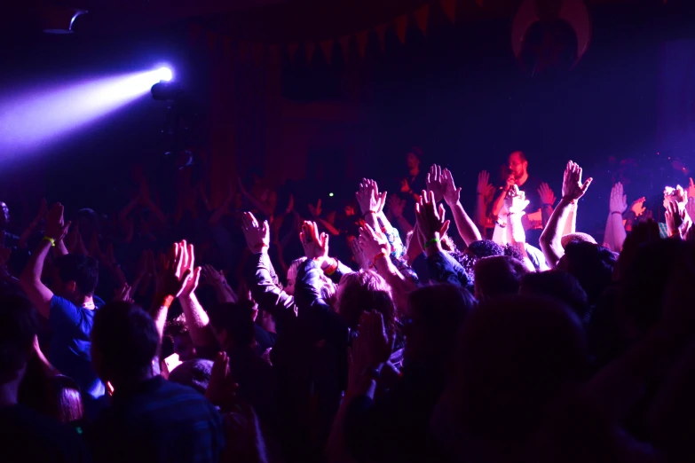 several people at a concert cheering while raising their hands