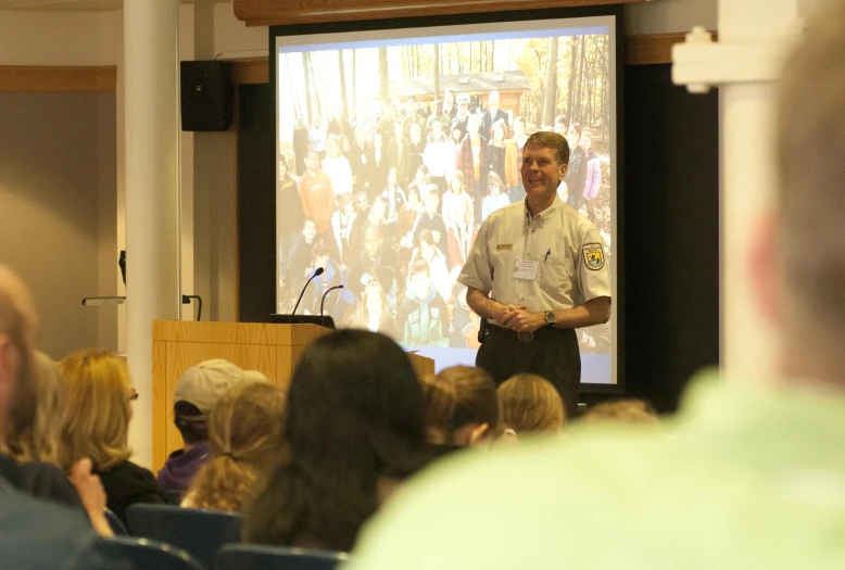 a man in uniform is giving a presentation at an audience