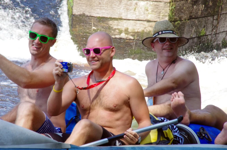 three men in rafts wearing hats and shades taking a selfie