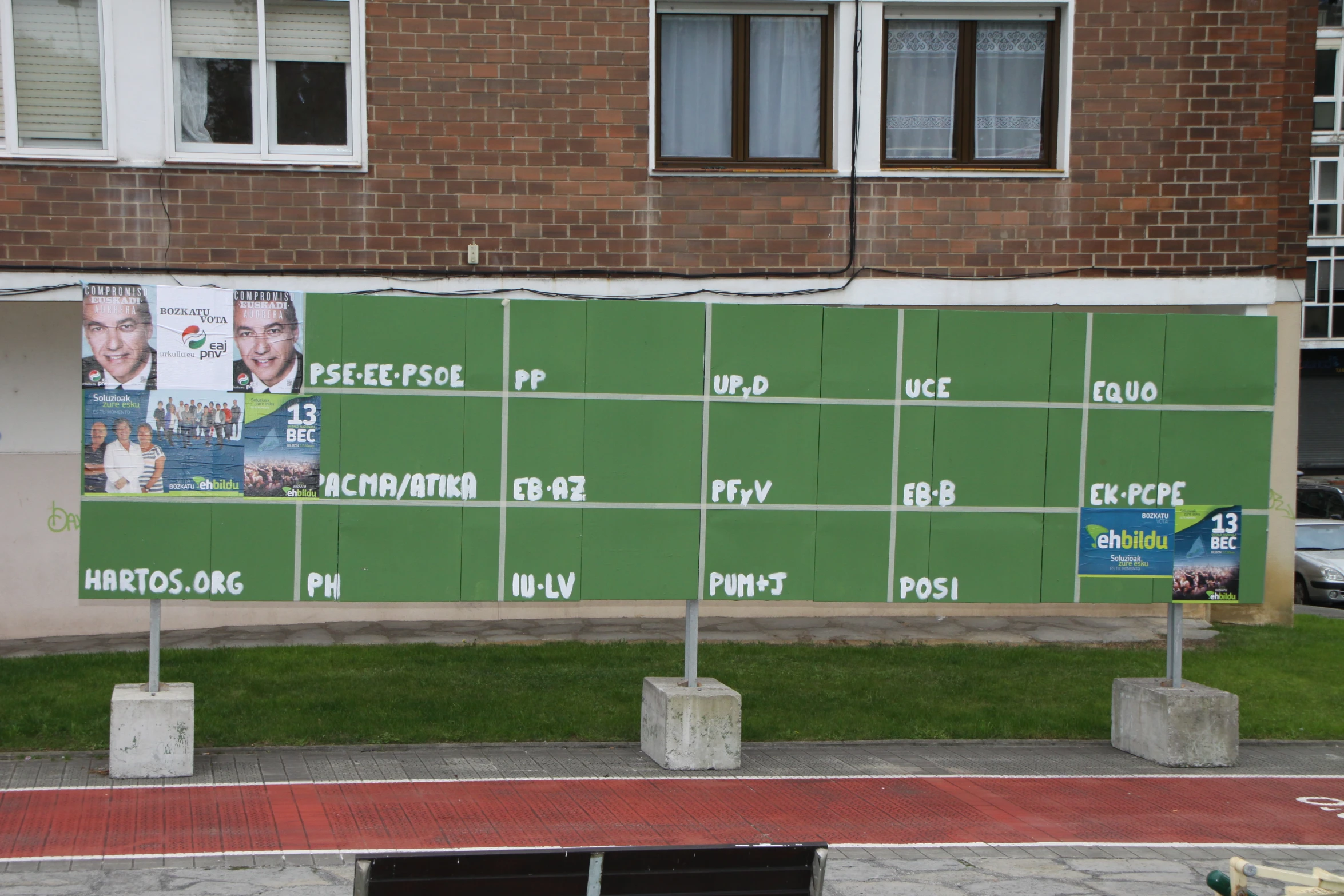 a street with a green wall and posters on it