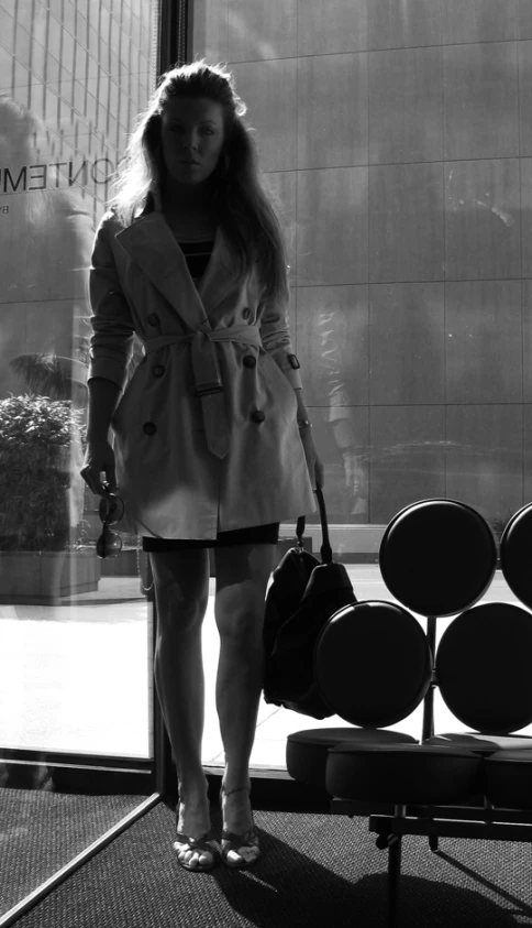 black and white pograph of a woman holding purse next to a bench