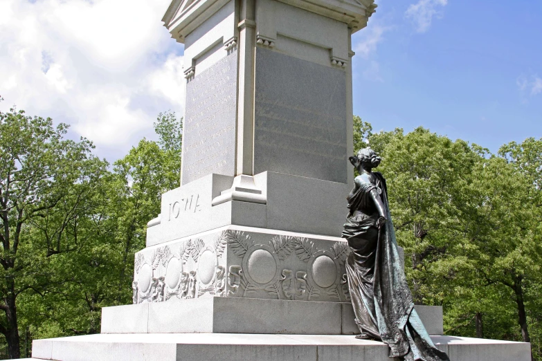 a statue with a long veil on top sitting in the middle of a park