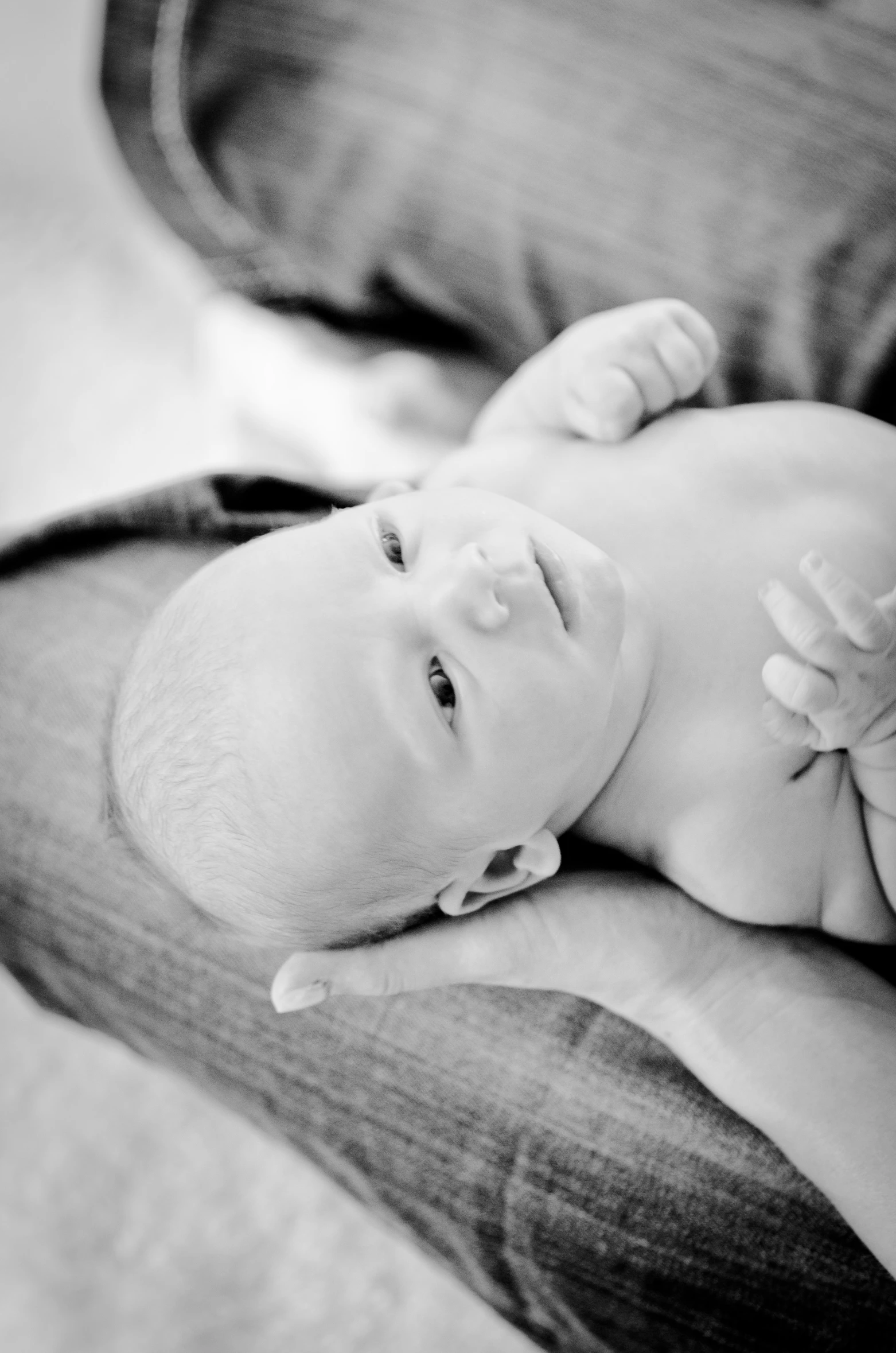 baby lays on her back in a man's lap and holds its head on his other arm