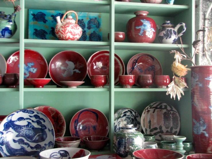 a wall that has plates on it in front of green shelving