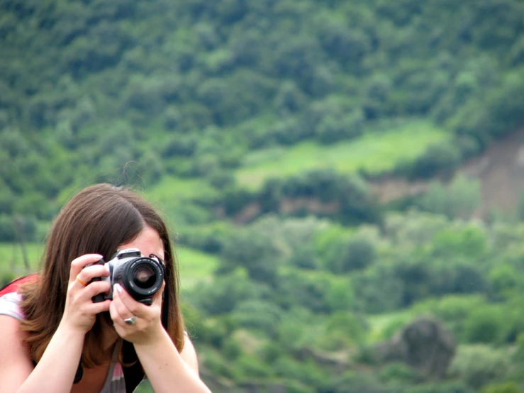 a woman taking a picture of some trees with a camera