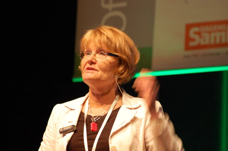 woman speaking at a lecture, with headset and name tag in background