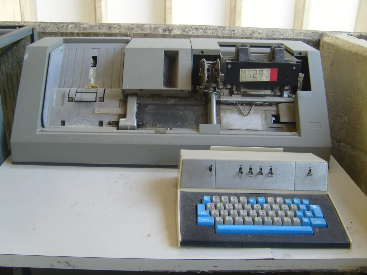 a blue keyboard sitting next to a typewriter on top of a desk