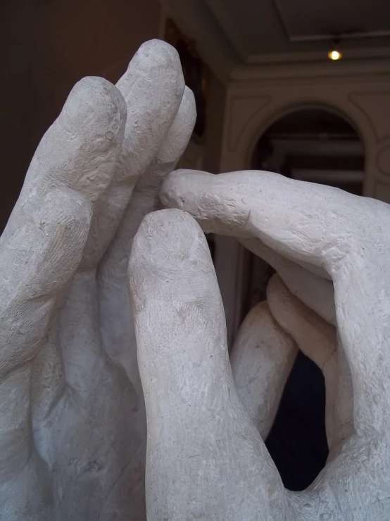 a white sculpture of two hands and a window in the background