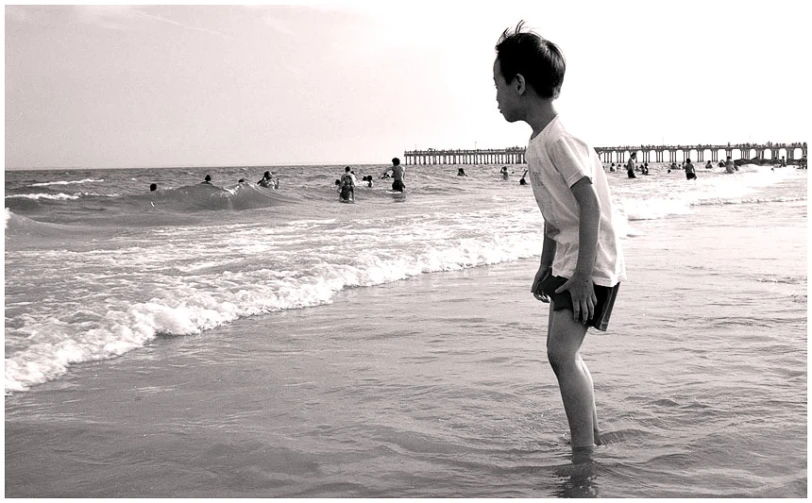 a boy standing on a beach holding a ball