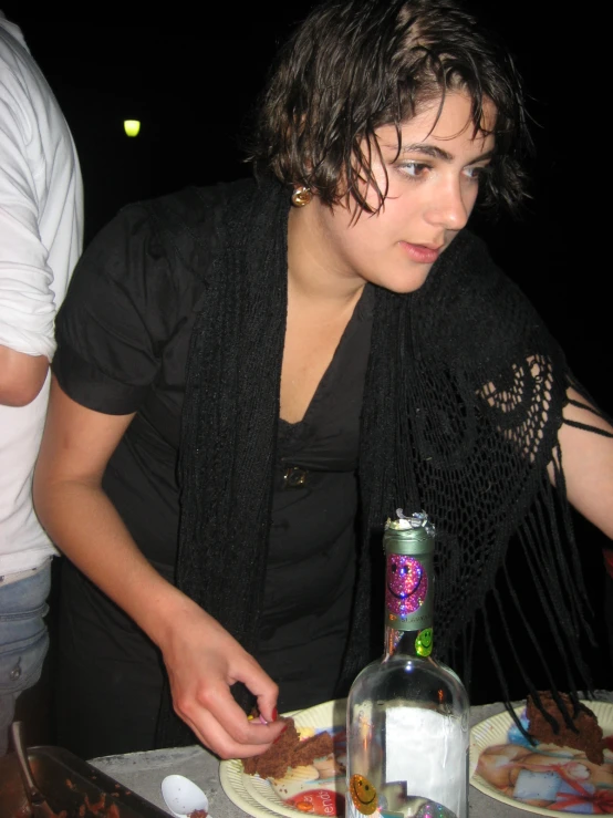 young woman standing at the table making a slice of cake