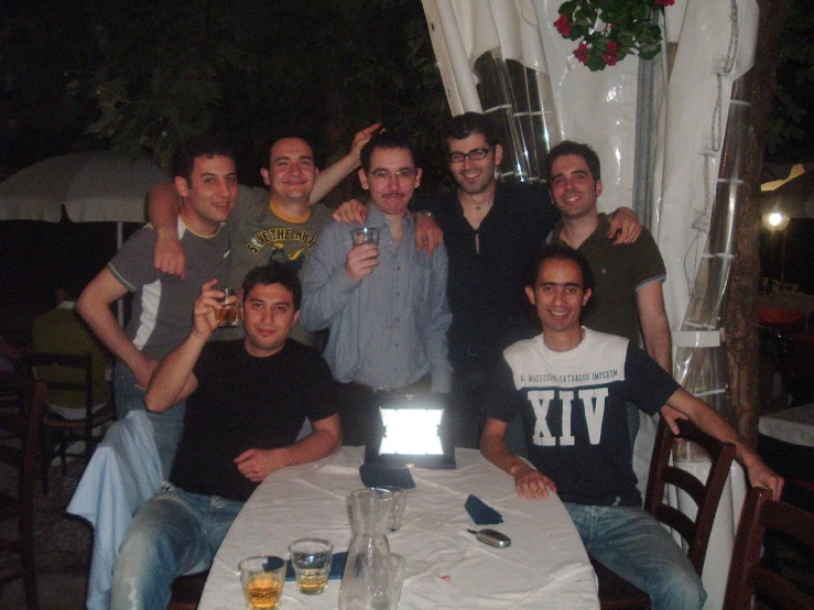 people posing for a group pograph at a table in the evening