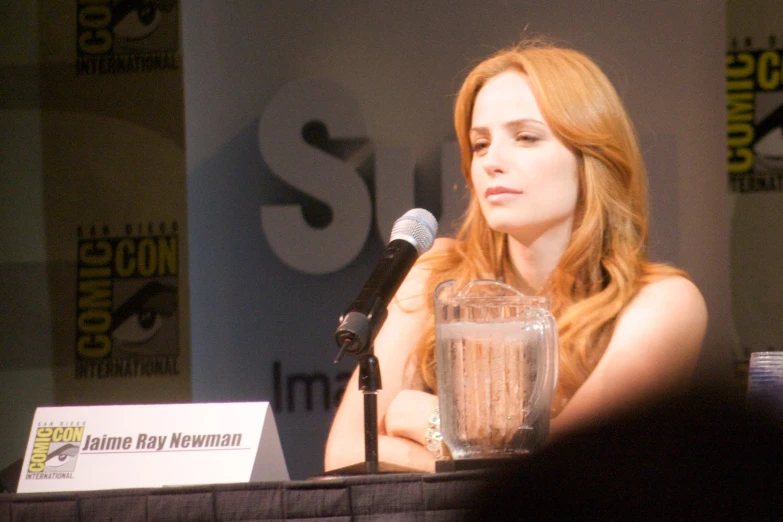 red - haired woman sitting in front of a microphone