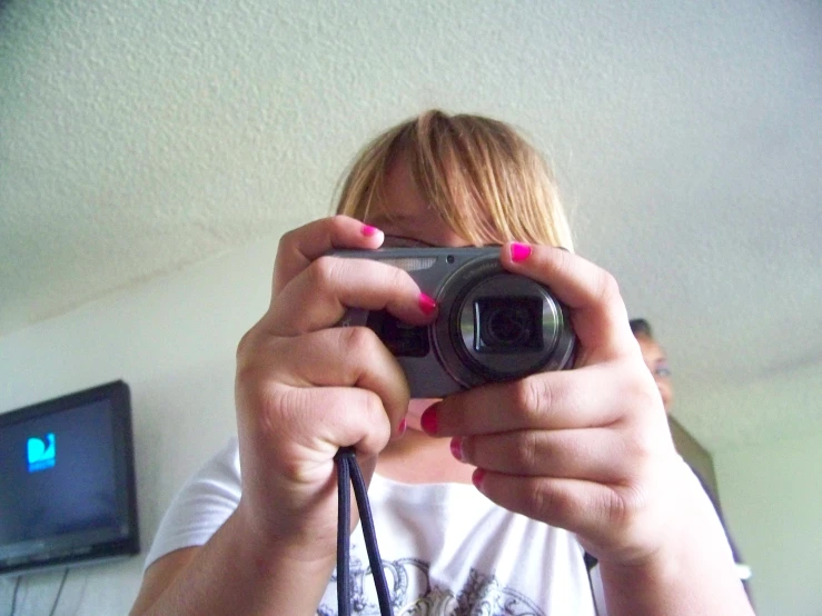 a girl holding up a digital camera to take a po