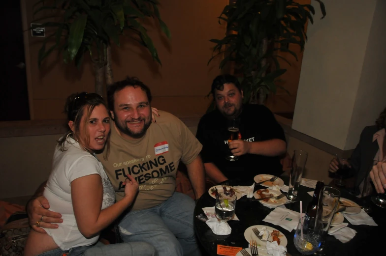 three friends sitting at a table with drinks and plates