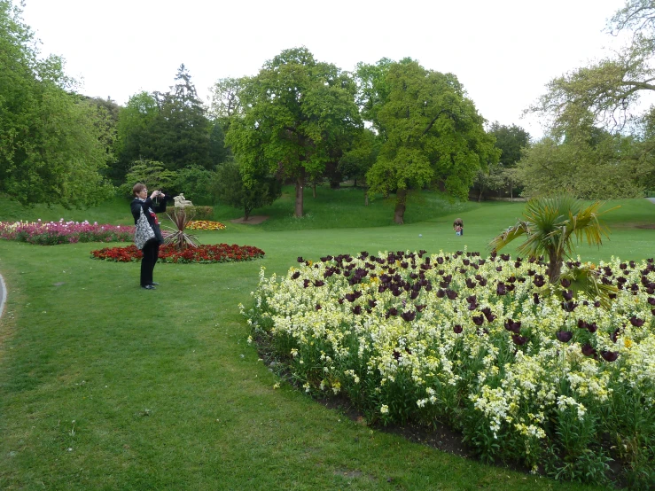 a lady holding her arms up while standing in a garden