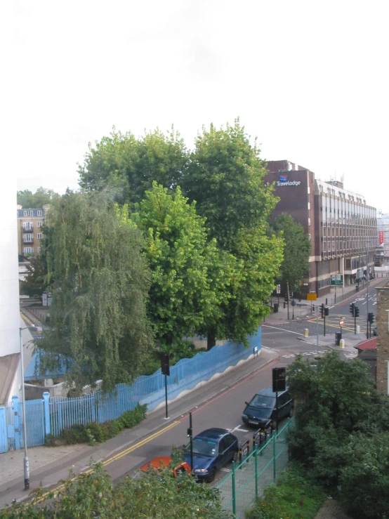 a view of a busy city street with a blue fence