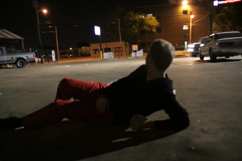 a man lies on the side of a street at night