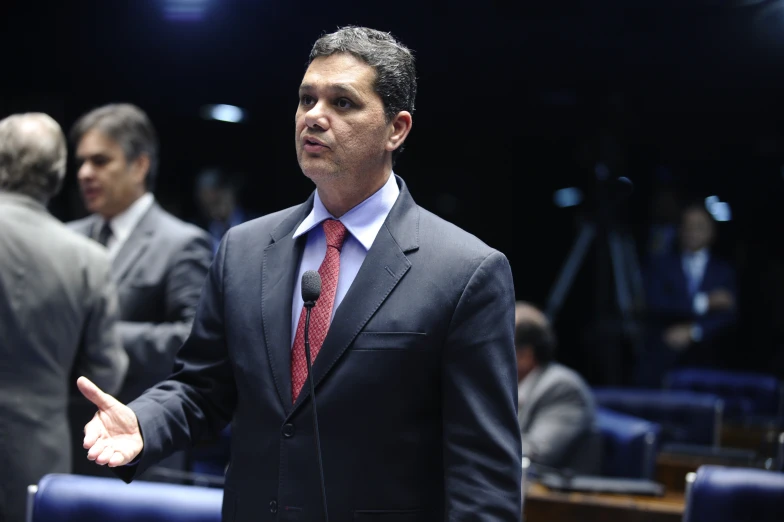 a man with his hands out to speak in a conference