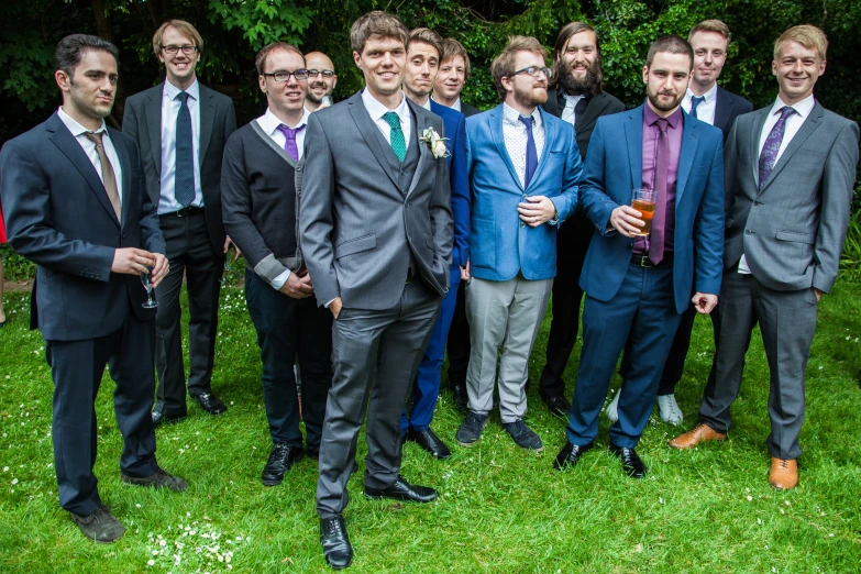 a group of men dressed in suits stand together on the grass