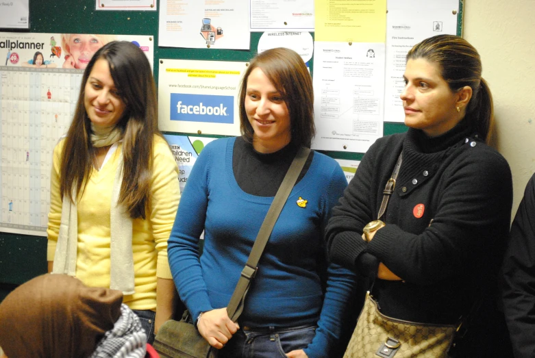 four women are standing in front of a bulletin board