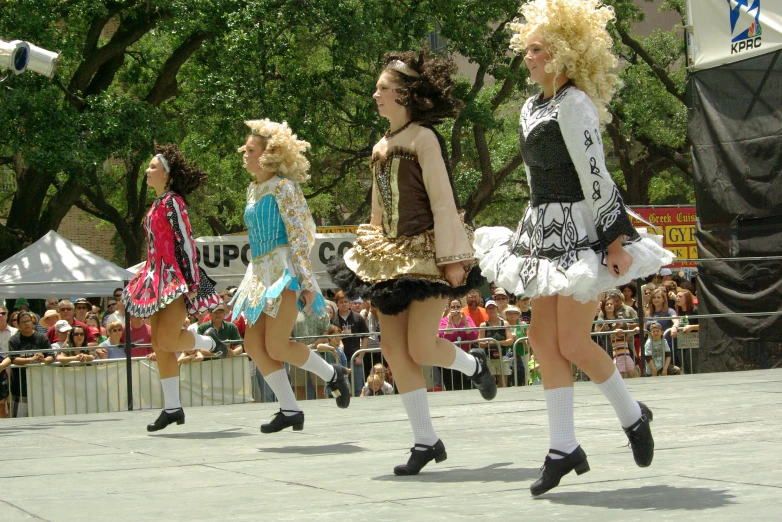 three girls in costumes are walking near people