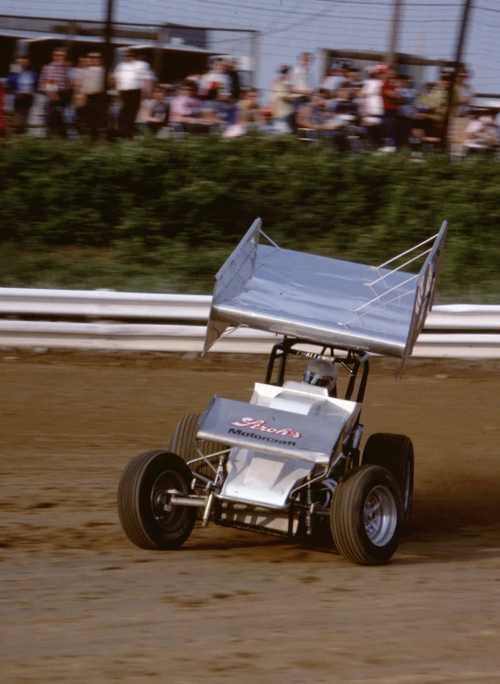 a person racing a buggy with spectators behind him