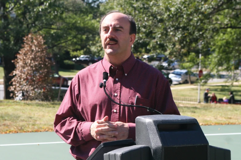 a man wearing glasses speaks in front of a microphone