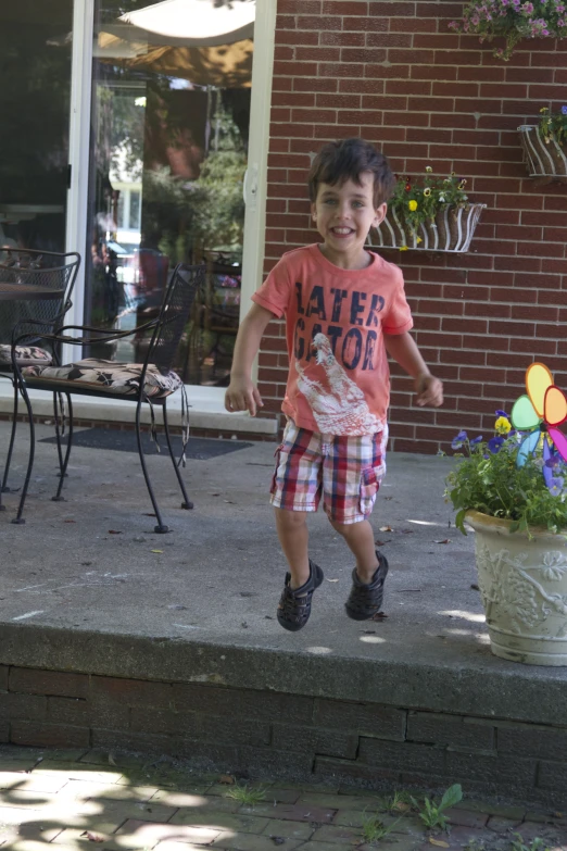 little boy with his hands in his pockets standing on a stone step