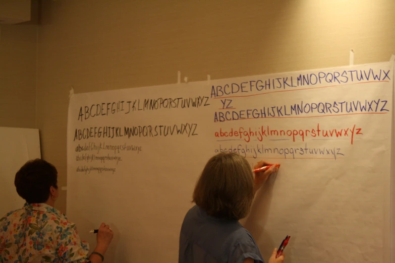 two people writing on a whiteboard with magnets