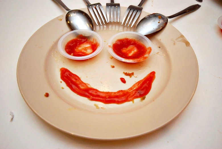 a plate with tomato ketchup in the shape of a smiley face