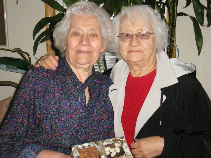 two elderly women holding a small box of chocolates