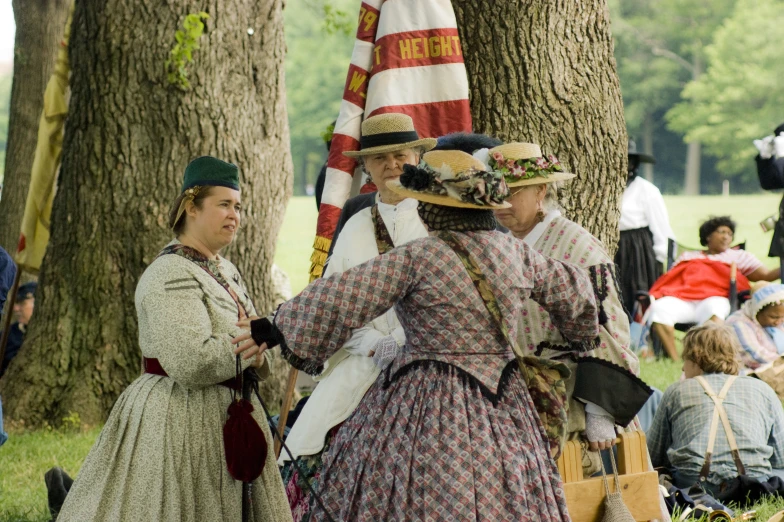 a group of women sitting in the grass near a tree