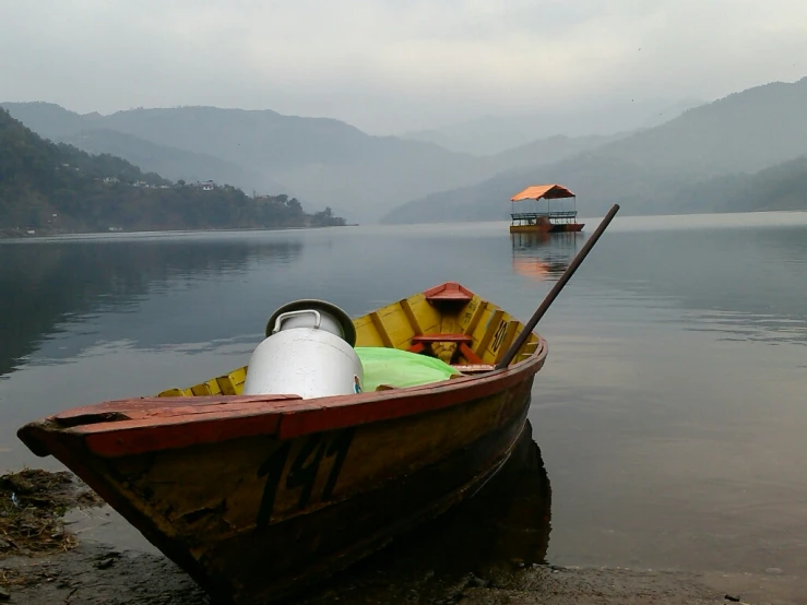 a boat in a lake on the shore, with a yellow awning above it