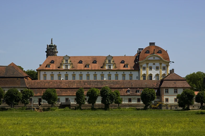 a large building with a steeple and clock tower next to a large field