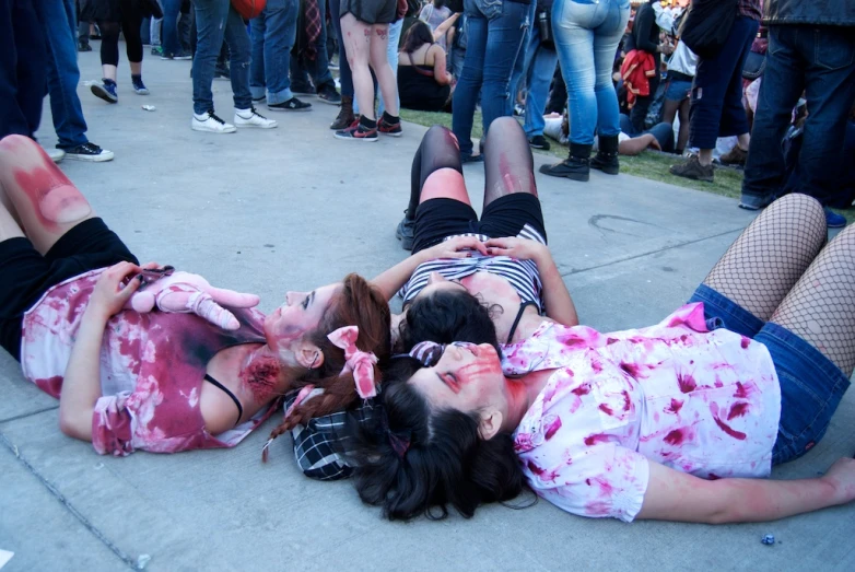 two young women dressed in zombie costumes lie down