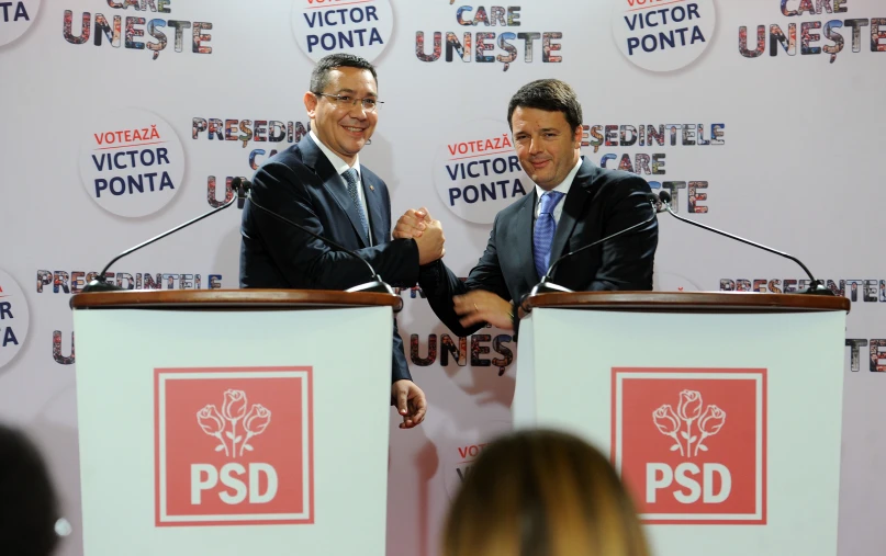 two men standing behind a podium on stage