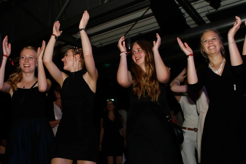 girls dancing with their hands up while wearing black dresses