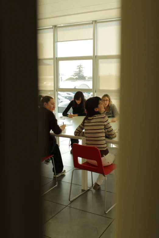 people sitting at tables eating while one looks out the window