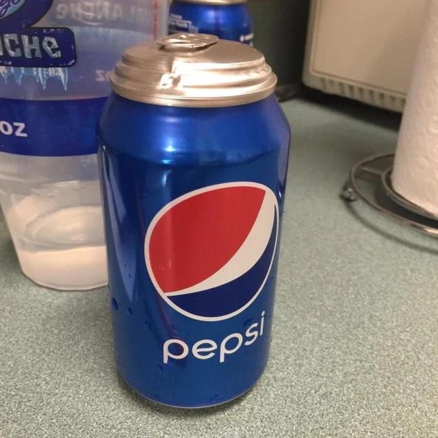 there is a blue pepsi can next to a glass of water