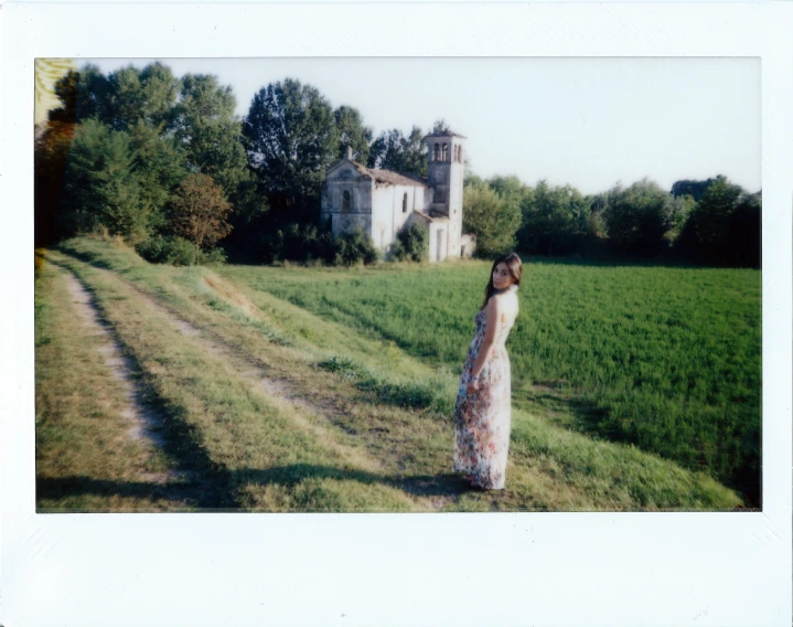 a woman is standing in the grass in front of a house