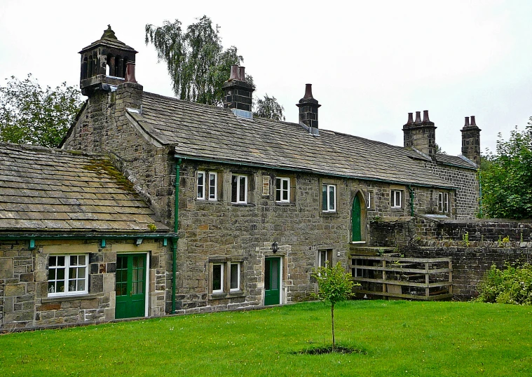 an old stone house sitting on top of a lush green field