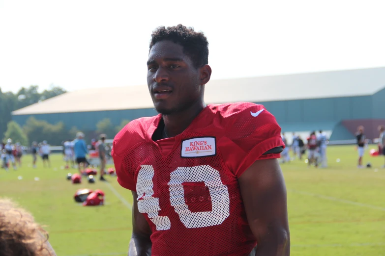 a young man in a football jersey on the sidelines