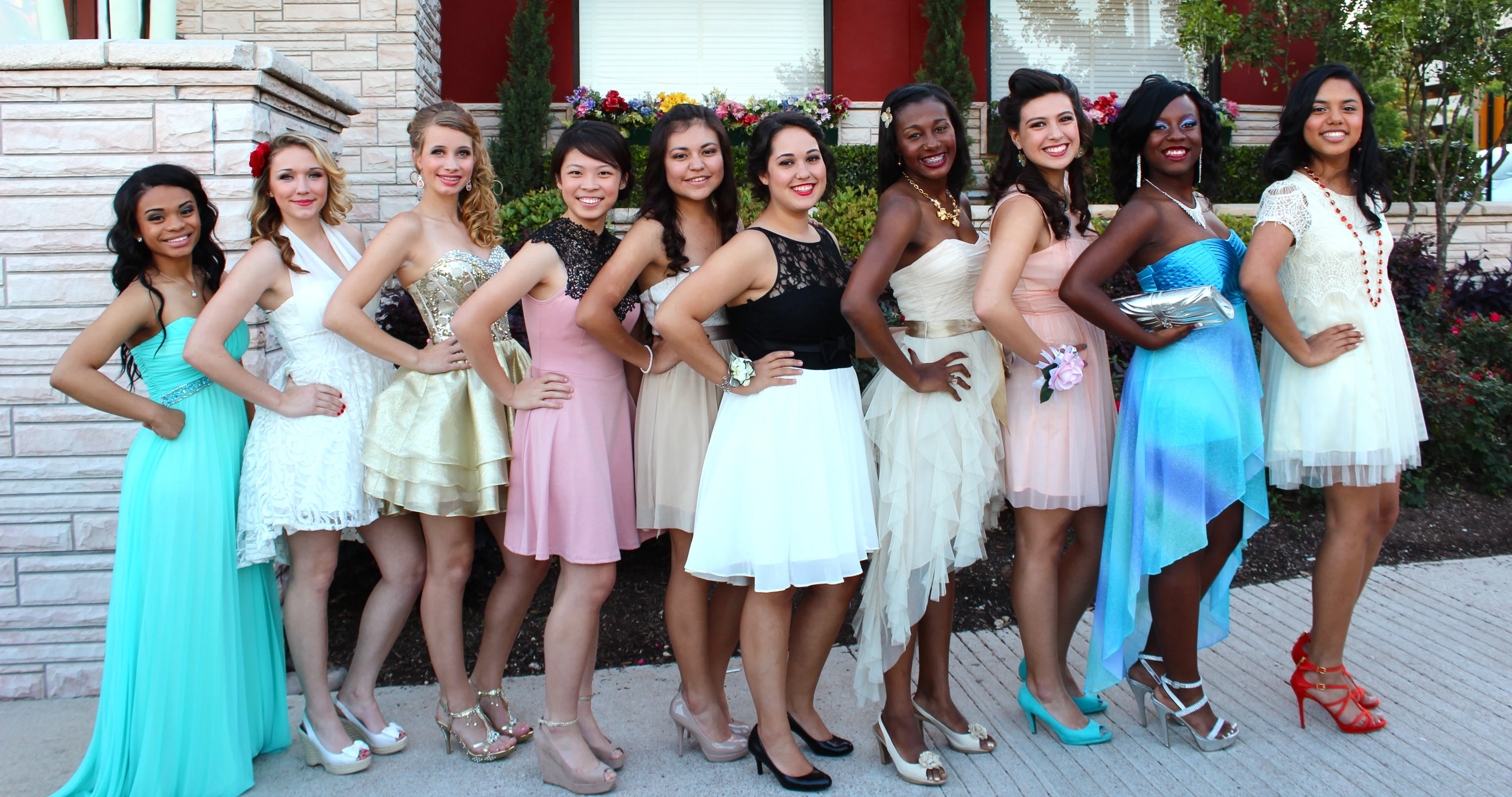 six beautiful women in dresses standing together on the sidewalk