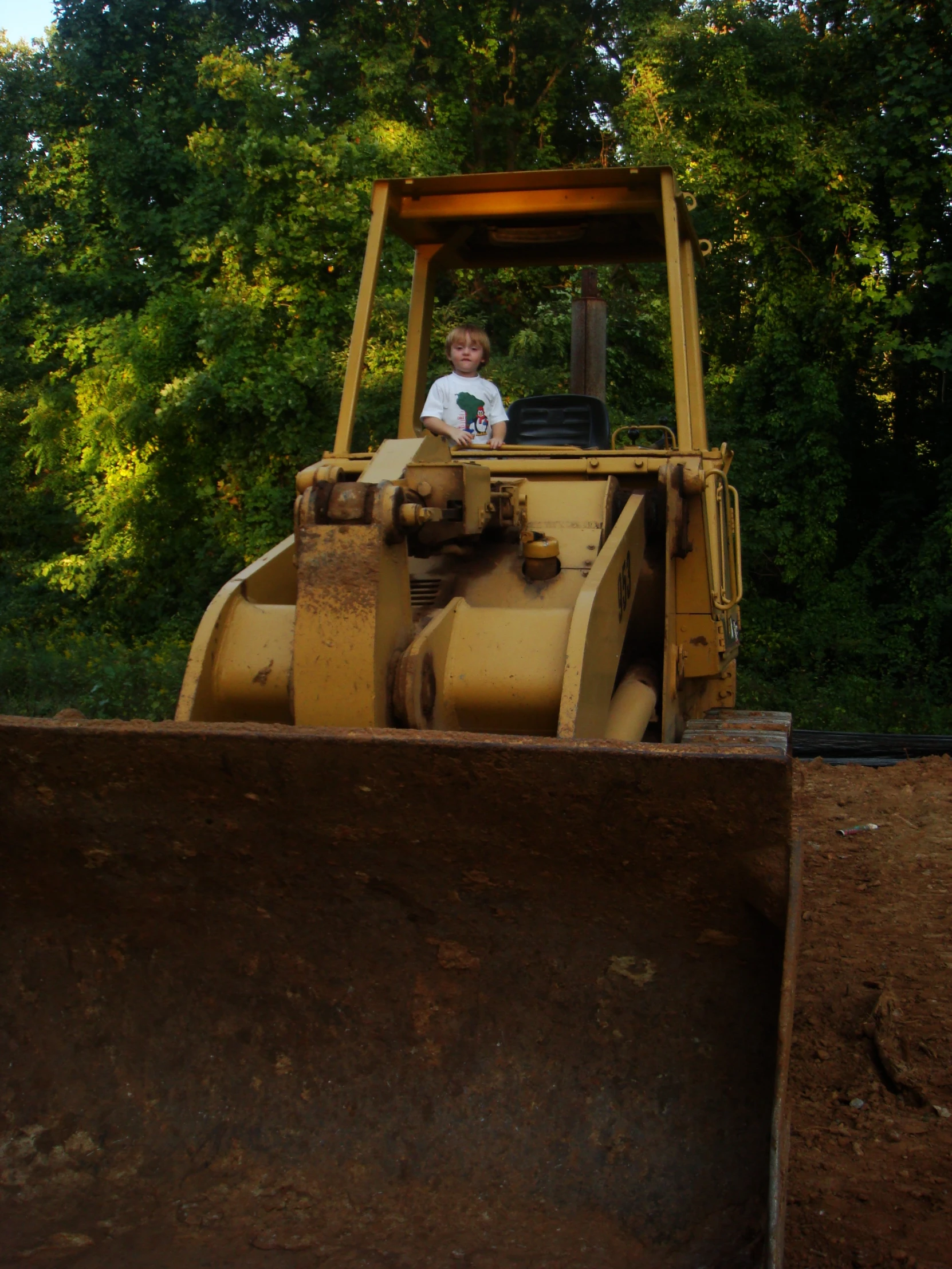 a young man riding on top of a large yellow bulldozer