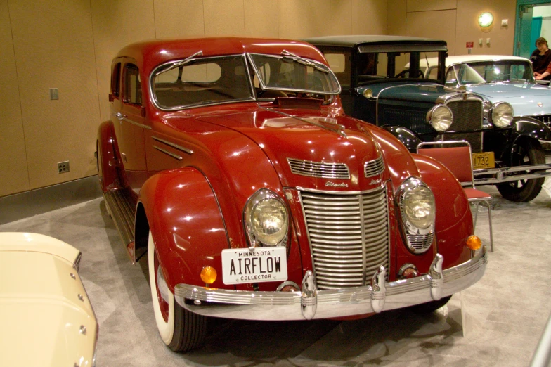 a couple of red classic cars on display at a museum